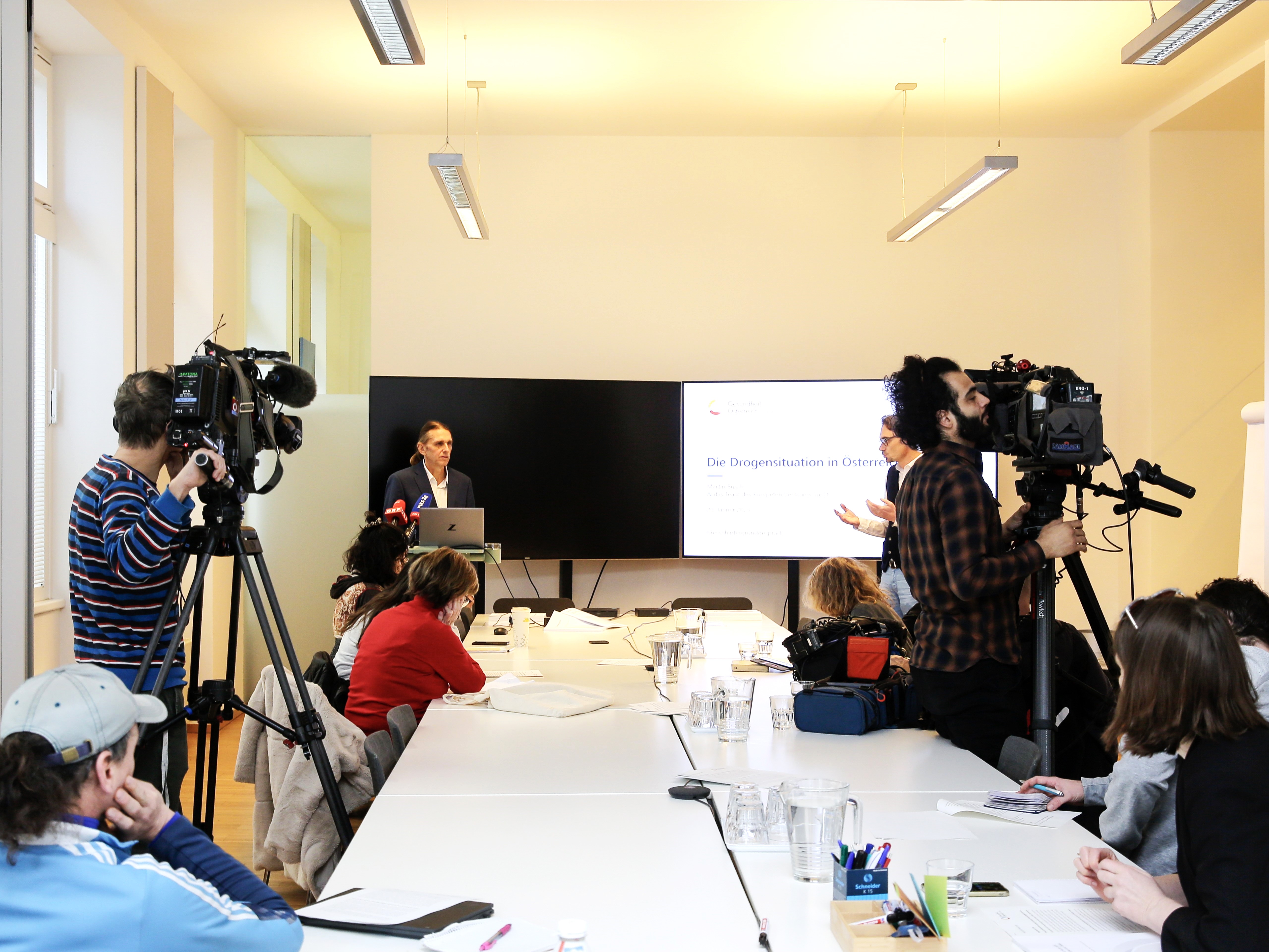 Pressekonferenz zur Drogensituation in Österreich – Martin Busch präsentiert aktuelle Daten, Journalist:innen und Kamerateams dokumentieren die Veranstaltung.