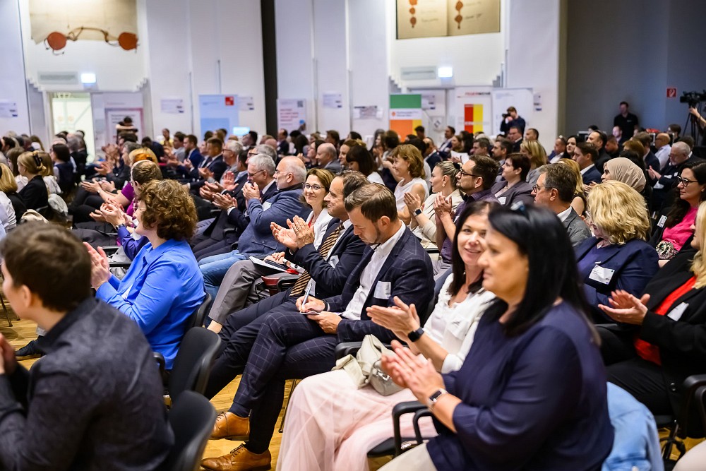 Applaus im Publikum während der Preisverleihung des Österreichischen Verwaltungspreises 2025. Die Teilnehmenden sitzen dicht beieinander, viele lächeln und applaudieren.