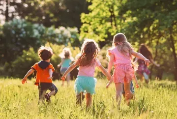 Drei Kinder spielen auf einer Wiese.