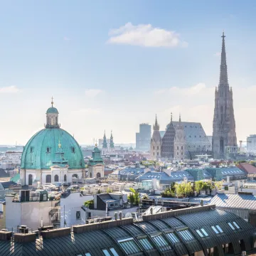 Blick über die Wiener Innenstadt mit Stephansdom und Peterskirche an einem sonnigen, wolkenarmen Tag – Sinnbild für heiße Sommer in der Stadt und den städtischen Hitzeschutzplan.