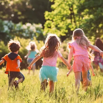 Drei Kinder spielen auf einer Wiese.