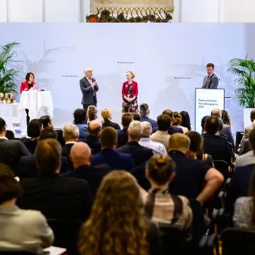 Verleihung des Österreichischen Verwaltungspreises 2025 durch das Bundeskanzleramt – Publikum und Redner:innen auf der Bühne während der Auszeichnung.“