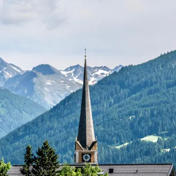 Kirchturm von Bad Hofgastein vor Alpenkulisse – Veranstaltungsort des European Health Forum Gastein 2025.