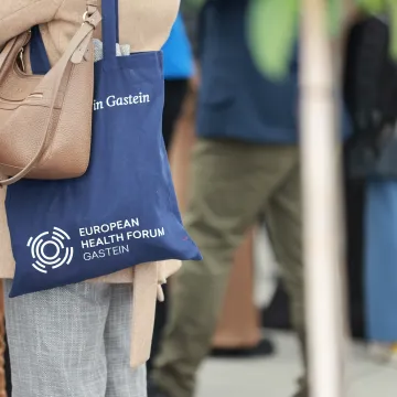 Person hat Jutebeutel mit Logo vom European Health Forum 2025 in Bad Hofgastein umgehängt.