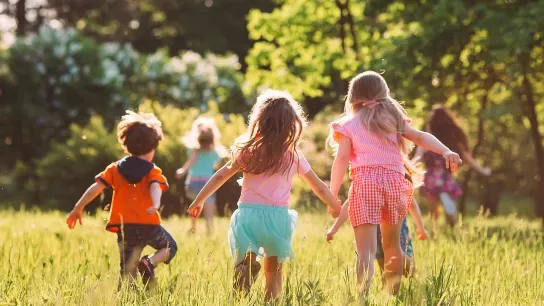 Drei Kinder spielen auf einer Wiese.