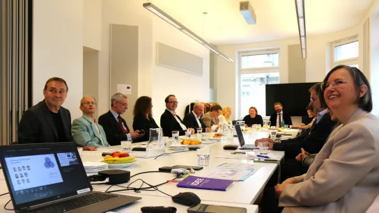 © GÖG / Georg Gatnar Ministerin Korinna Schumann sitzt gemeinsam mit Vertreter:innen der Gesundheit Österreich GmbH an einem langen Konferenztisch. Die Teilnehmenden blicken lächelnd in Richtung Präsentation, auf dem Tisch liegen Unterlagen und Obst.