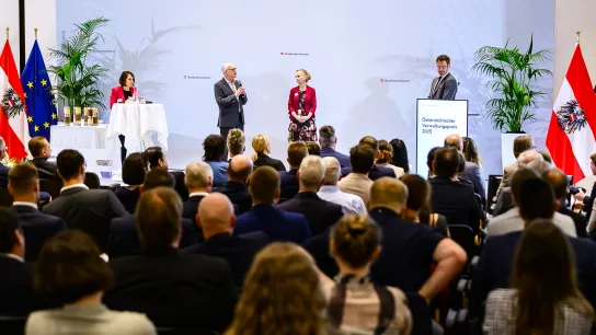 © Marko Kovic Verleihung des Österreichischen Verwaltungspreises 2025 durch das Bundeskanzleramt – Publikum und Redner:innen auf der Bühne während der Auszeichnung.“
