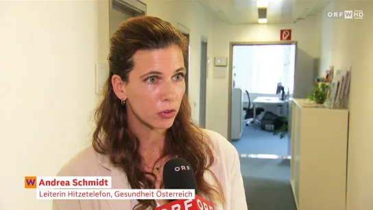 © Wien heute Screenshot eines ORF-Interviews: Eine Frau spricht in einem Bürogebäude in ein ORF-Mikrofon. Die Bauchbinde lautet „Andrea Schmidt – Leiterin Hitzetelefon, Gesundheit Österreich“. Der Beitrag in „Wien heute“ trägt den Titel „Hitzetelefon bietet Rat zu Gesundheit und Hitze“.